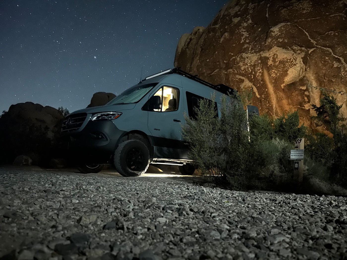  is parked on dirt facing vast green fields and snow-capped mountains.|Cozy night camping! This RV rental — photo 3
