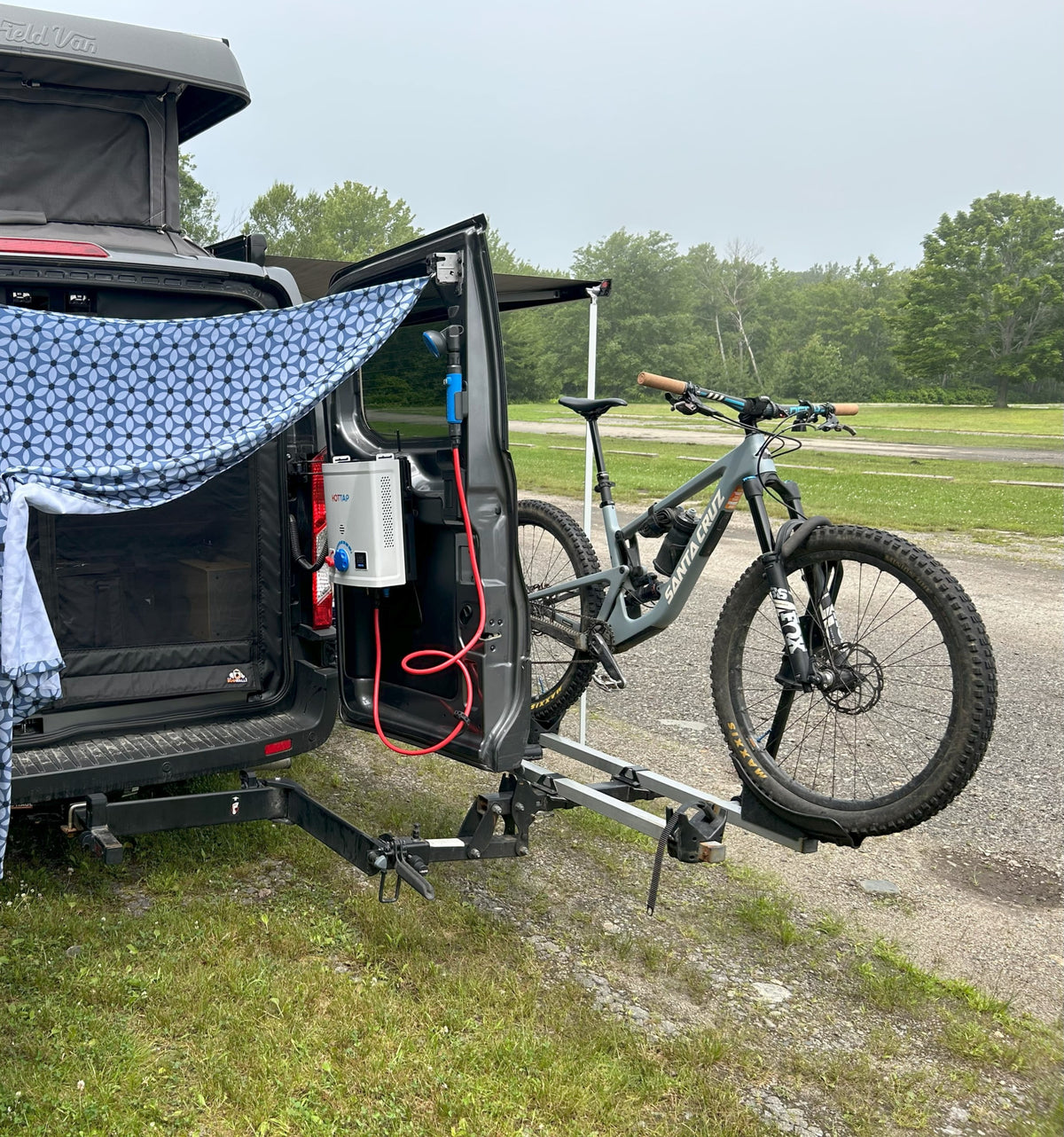 This RV rental camper van features a pop-top, outdoor shower, and a mountain bike on its rear rack, parked in a grassy area. — photo 7