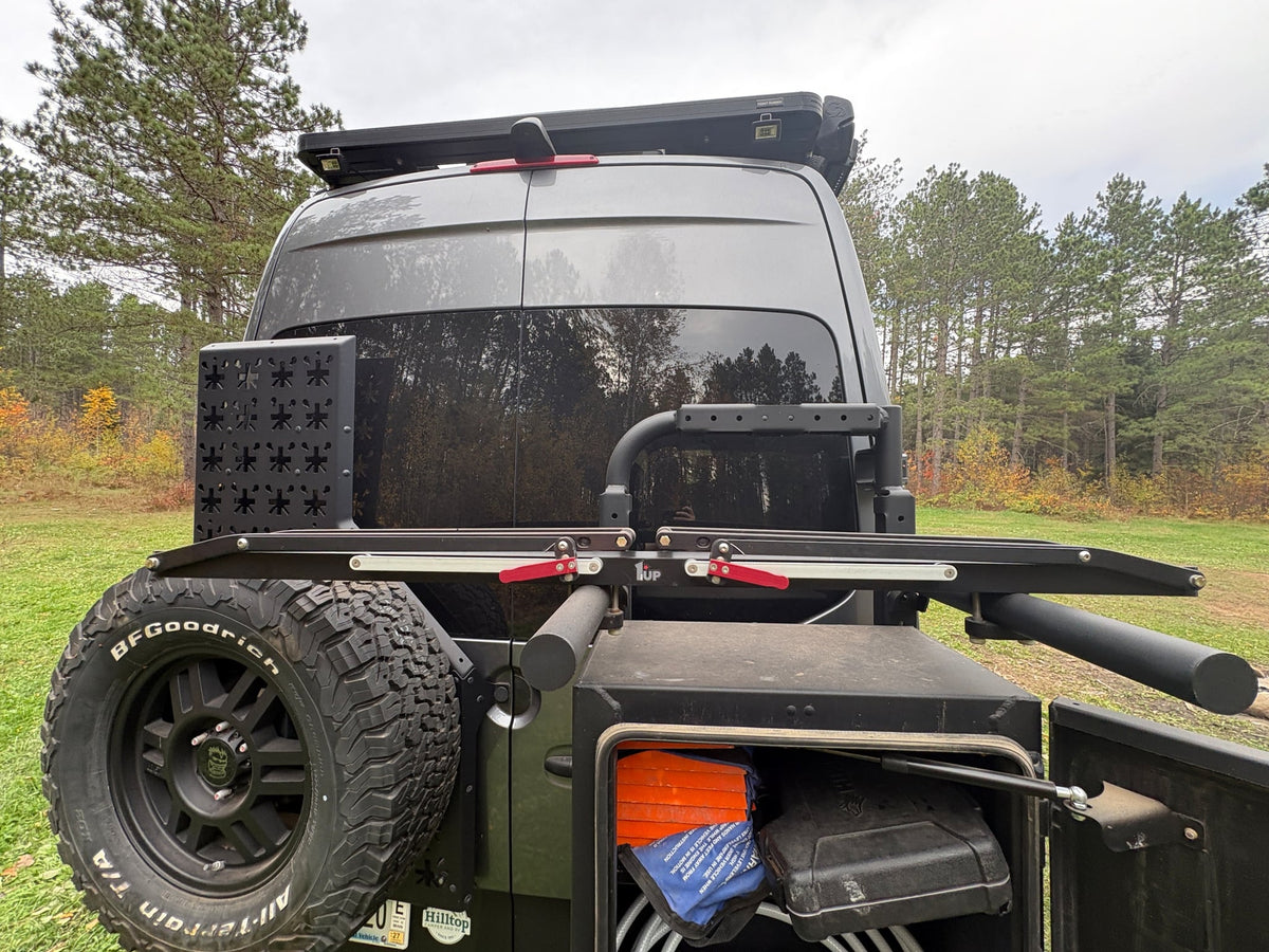  parked in a forest clearing with a fire pit.|Grey adventure RV rental with off-road tires — photo 16
