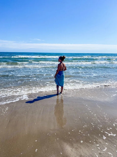 Person on beach, looking at serene ocean views. Find coastal bliss on your next RV rental trip.