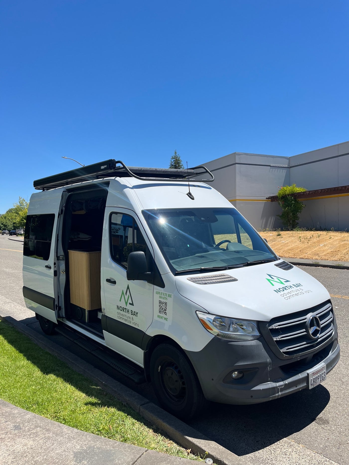 White Mercedes Sprinter adventure van, branded "North Bay," available for rv rental with its side door open. — photo 3