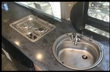 RV rental kitchen: stainless steel sink, two-burner stove, and dark speckled countertop for easy meal prep.