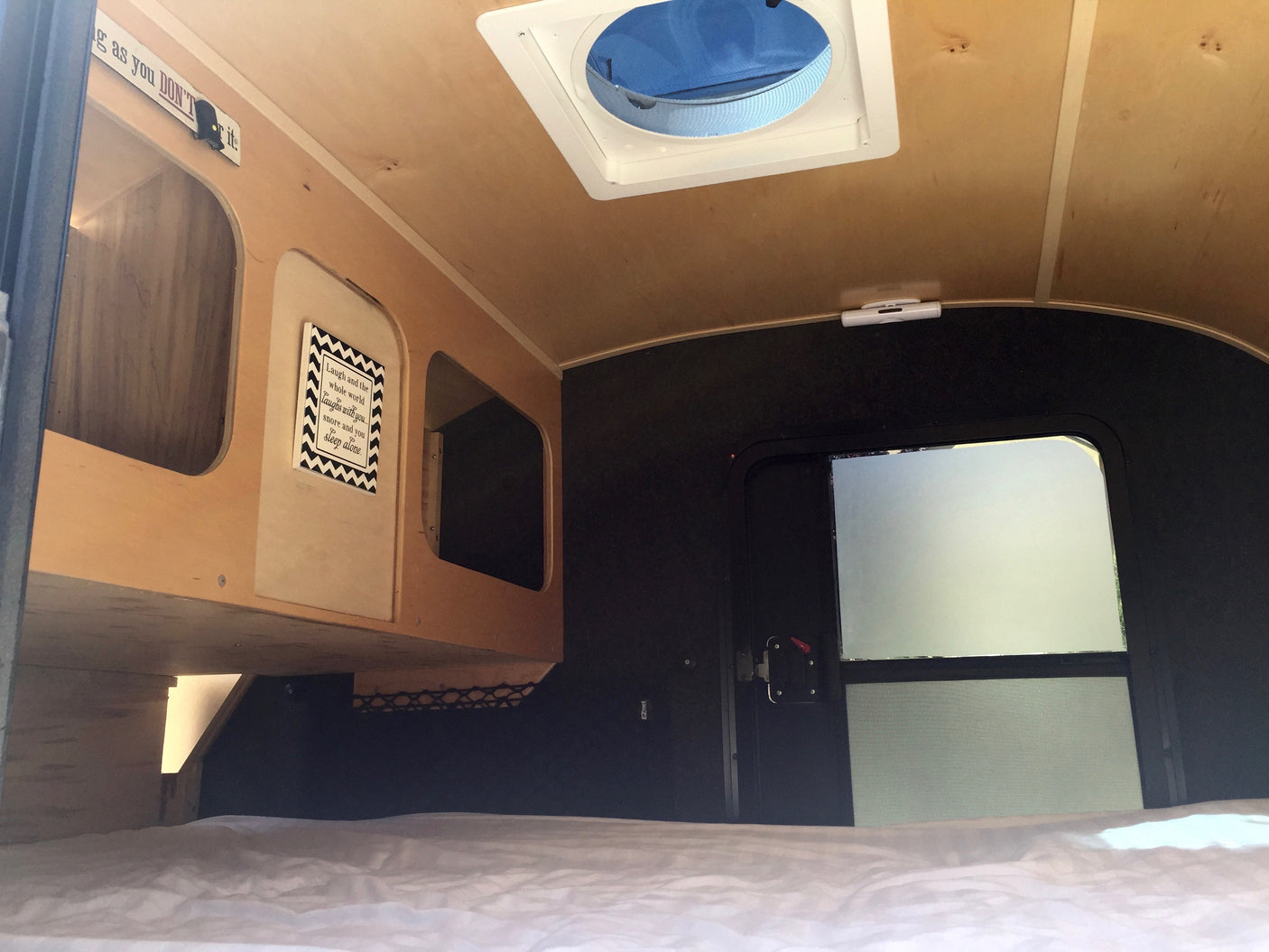 Cozy RV rental interior: bed, wooden storage, and overhead fan for comfortable mobile living.