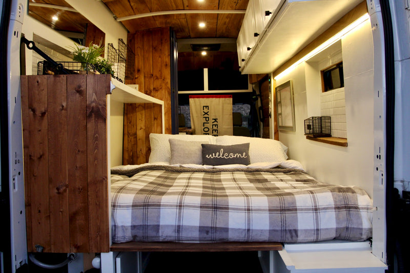 Cozy RV rental interior: a comfy plaid bed, warm wood paneling, and bright ambient lighting for your travels. — photo 3
