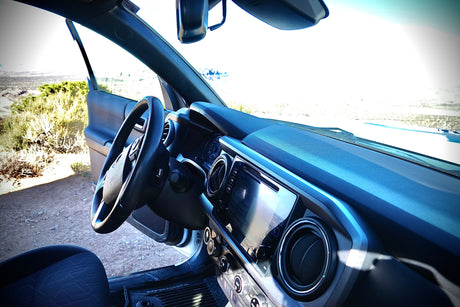Interior view of a Toyota Tacoma truck with an open door to a vast dry landscape, ideal for travel or an rv rental.