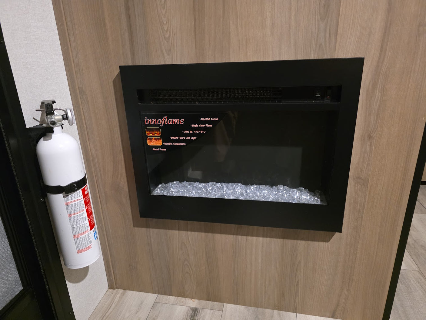 Cozy RV rental interior with an electric fireplace for warmth and a mounted fire extinguisher for safety.
