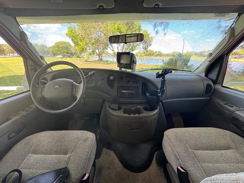 RV rental interior: driver's view from the front seats, showing a Ford dashboard & scenic lake through the windshield. — photo 4