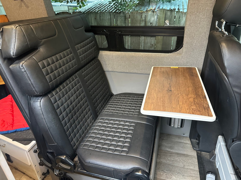  wood-look table and a protective mesh screen.|RV rental interior with a black — photo 19