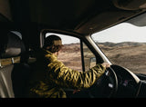Driving an RV rental through a vast, arid landscape of rolling hills. A person in a van enjoys sunlit desert views.