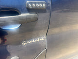 Dusty blue RV rental door featuring a keyless entry keypad, door handle, and a script 'Grateful' emblem. Close-up view.