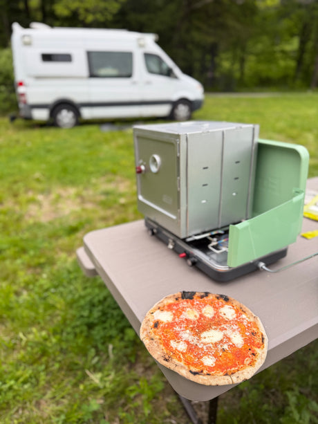Freshly baked pizza made with a portable oven next to an RV rental. Ideal for camping and delicious outdoor meals.