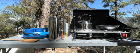 Enjoy camping meals with our RV rental! Outdoor kitchen includes a portable stove, kettle, French press, and blue dishes.