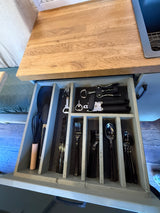 Organized kitchen drawer in an RV rental, featuring whisks, spatulas, bottle openers, corkscrews, and cutlery for your trips.