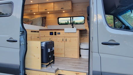 Step into this RV rental's clever van conversion, featuring a bed, kitchen, pull-out fridge, and toilet.
