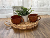 Cozy wooden cups and woven decor with a plant on a table. Perfect rustic touches for your RV rental adventure!