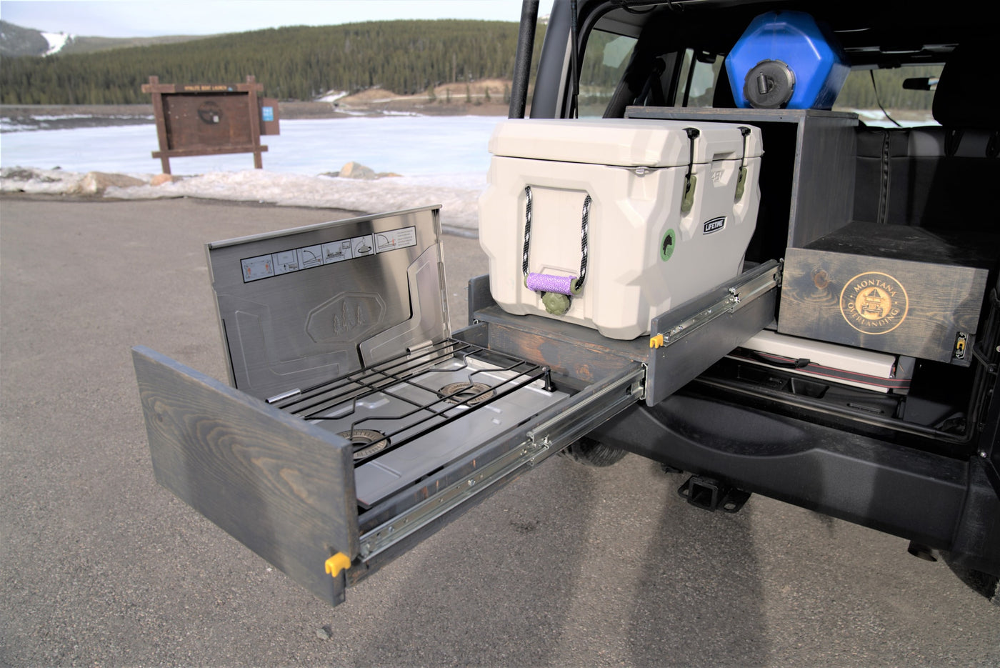 RV rental: vehicle's custom overlanding setup featuring a pull-out stove, cooler, and water jug by a frozen lake. — photo 7