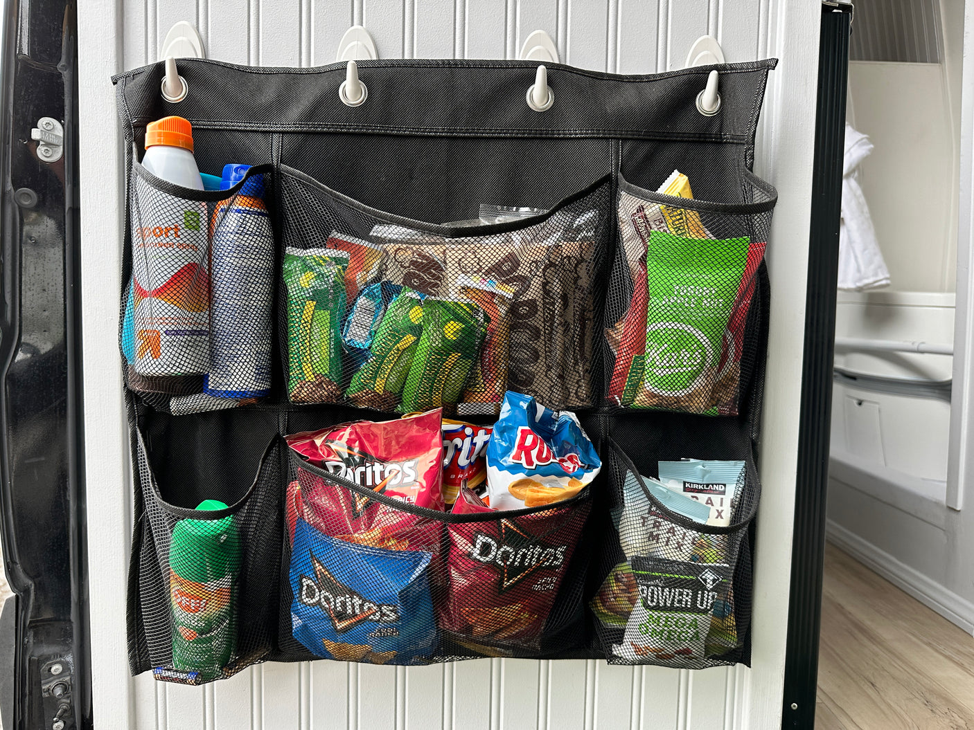 This RV rental features a hanging mesh organizer, stocked with snacks like chips and Power Up mixes, and bottles, ideal for maximizing space.
