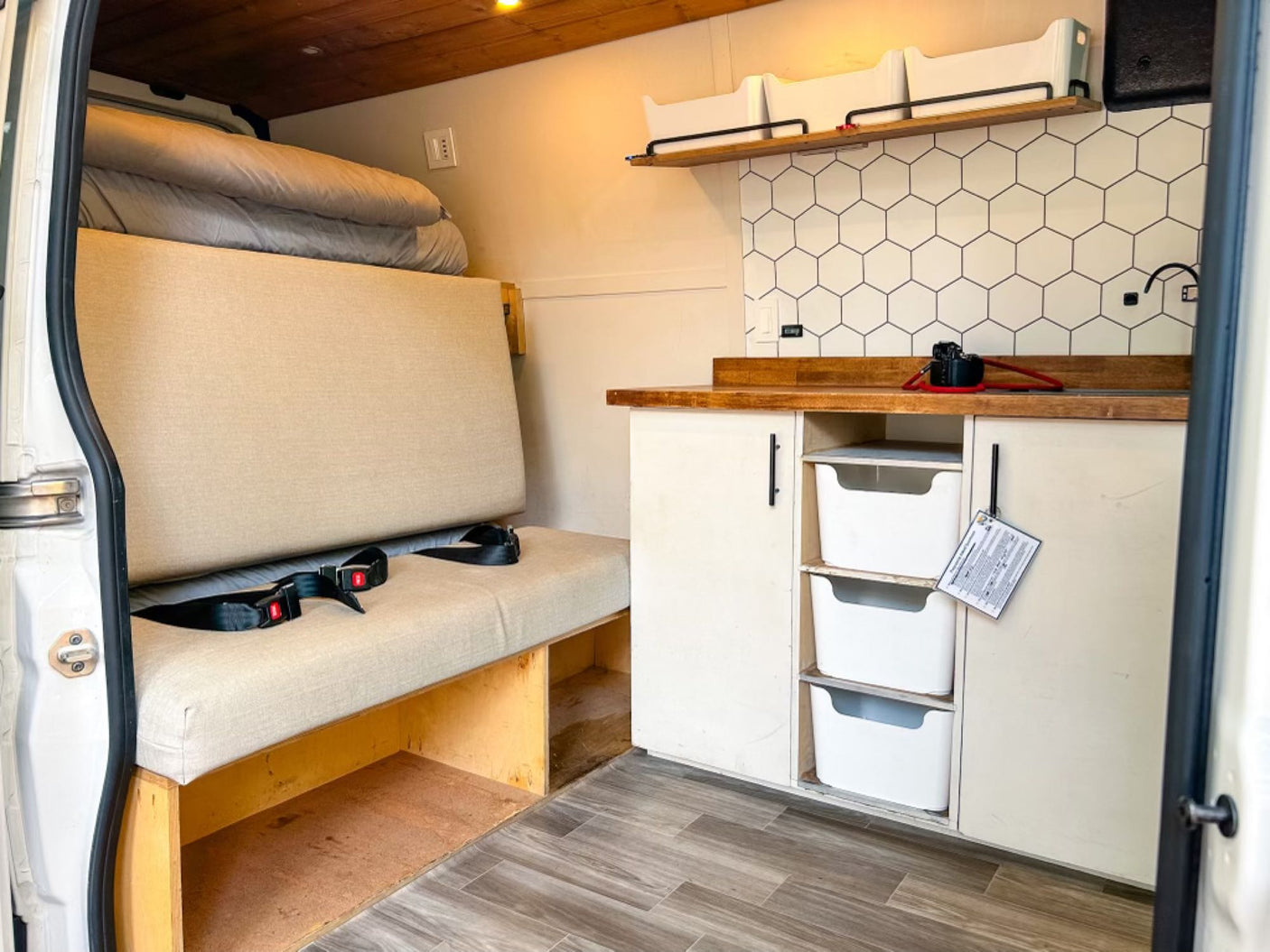Inside an RV rental: a compact kitchenette with hex tiles, comfy bench seating, and smart storage solutions for your journey.