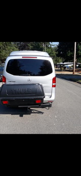 Rear view of a silver Mercedes Metris pop-top camper van with a Thule cargo box, great for RV rental.
