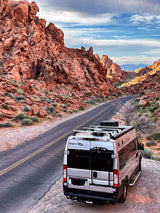 RV rental parked on a desert road, surrounded by stunning red rock canyons under a blue sky, perfect for a scenic road trip.