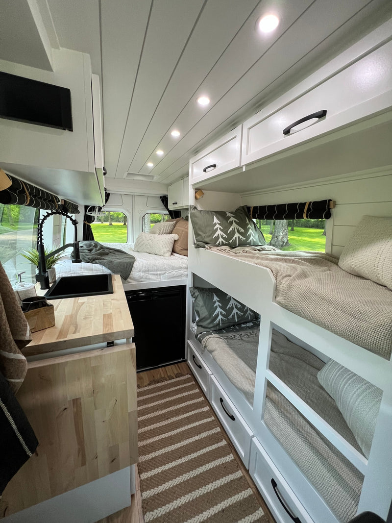 Modern RV rental interior features bunk beds, kitchen, a main bed, and built-in storage, perfect for travel. — photo 16