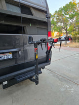Rear of a gray RV rental featuring an Allen bike rack attached to the hitch. Holding tank labels are visible below.