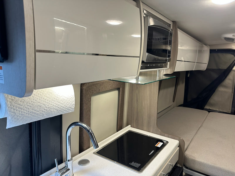  with its interior lit for a cozy campsite stay.|Rear view of a dark gray Thor Tellaro camper van rv rental with a bike rack — photo 2