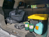 Camping gear in the back of an RV rental: Coleman bag, propane tanks, hammock, and storage bin, ready for adventure.