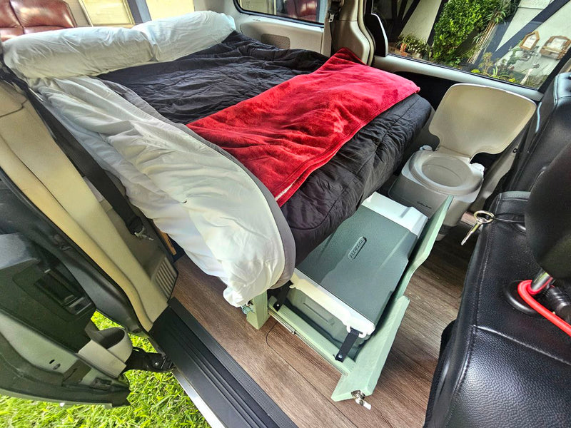Interior view of an RV rental van, showing a bed, portable toilet, and cooler for compact living & travel. — photo 11