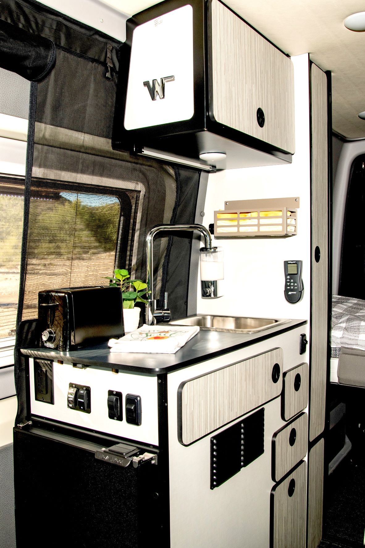  showing the front cabin with an overhead bed and safety features like a smoke detector.|Cozy Mercedes-Benz RV rental: Front cabin with plaid comforter and pillow laid out — photo 15