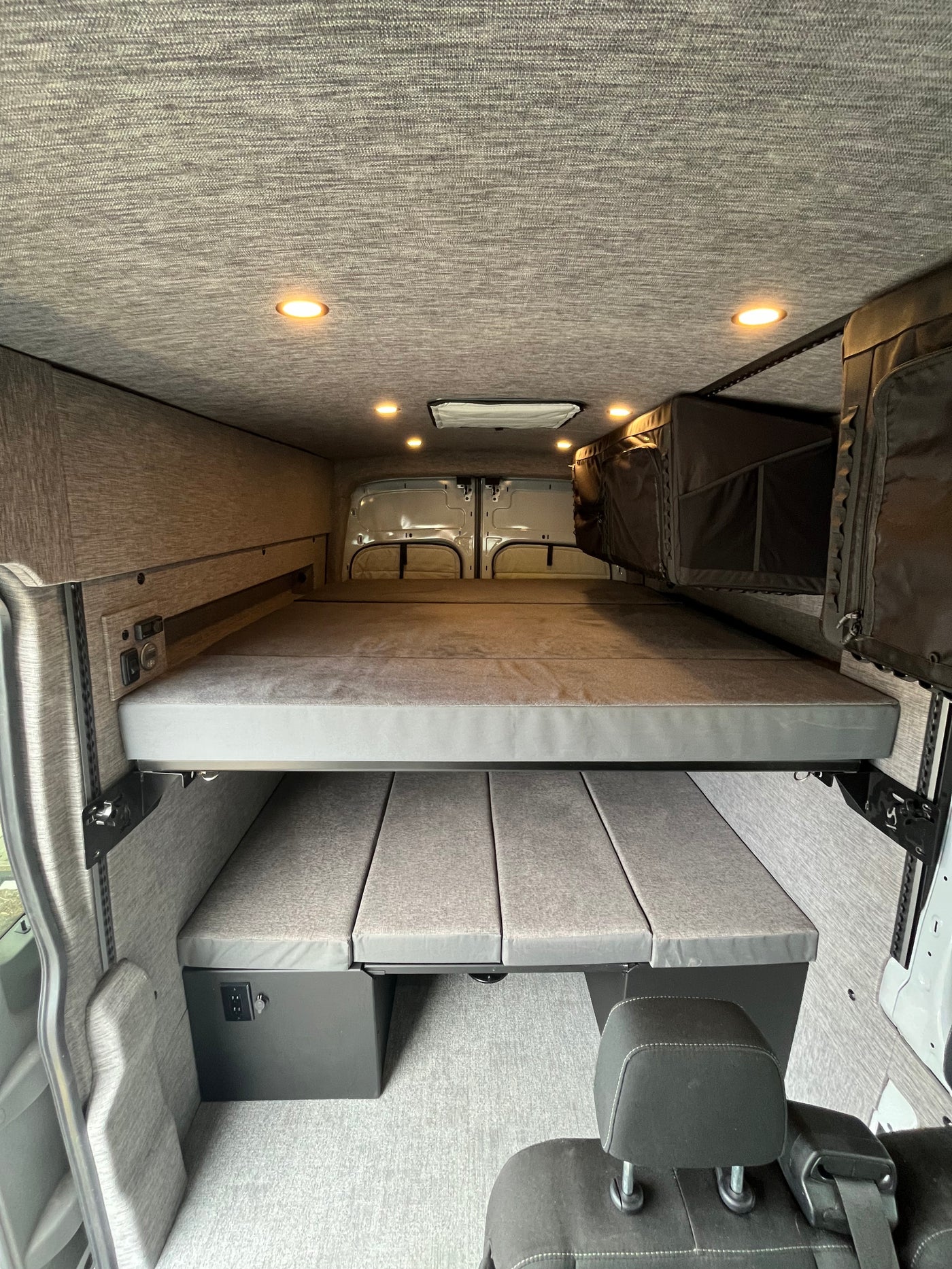 This converted van interior reveals a versatile two-tier modular bed setup, ideal for your next RV rental adventure. — photo 2