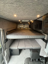This converted van interior reveals a versatile two-tier modular bed setup, ideal for your next RV rental adventure.