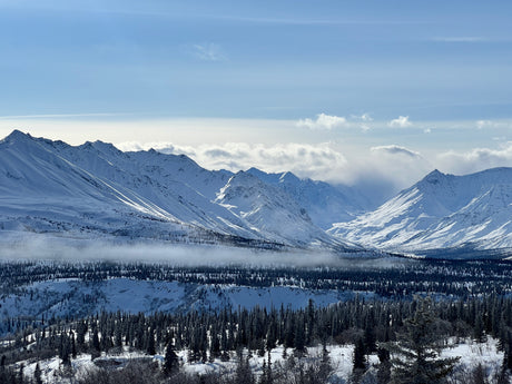 Stunning snow-covered mountains, frosted forests, and a misty valley, perfect for a winter RV rental adventure.