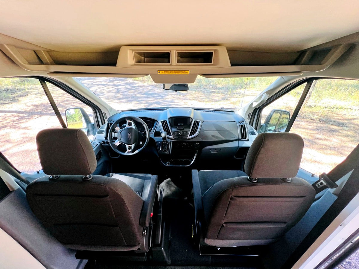 Inside an rv rental: View from rear of cabin showing driver's cockpit, seats, and road ahead. — photo 6