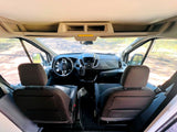 Inside an rv rental: View from rear of cabin showing driver's cockpit, seats, and road ahead.