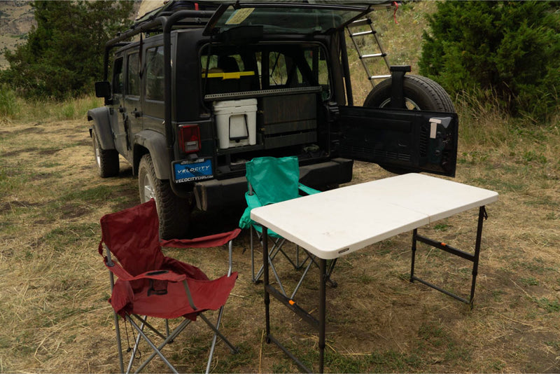  and utensils for easy outdoor cooking. Perfect for camping.|Ready for adventure: This RV rental Jeep shows a well-organized overland camping setup with chairs and a table.|Jeep Wrangler with a rooftop tent set up at golden hour — photo 4