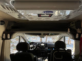 RV rental interior: looking forward in a camper van, showing the dashboard and a snowy forest outside.