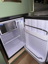 Explore this RV rental's compact, clean mini-fridge, featuring a freezer, wire shelf, and door compartments, perfect for your travels.
