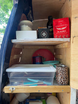 This RV rental features organized kitchen storage with shelves holding coffee, olive oil, sugar, plates, and utensils for compact travel.