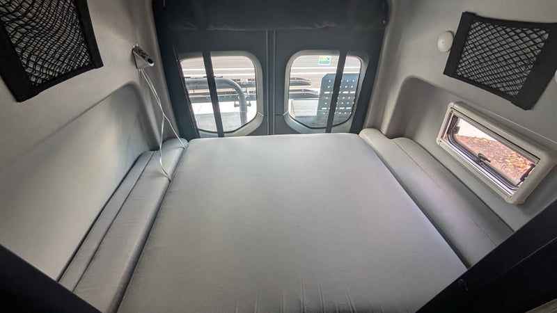  and wooden slatted shelves.|RV rental interior shows a camper van's compact living space with a bench seat — photo 7