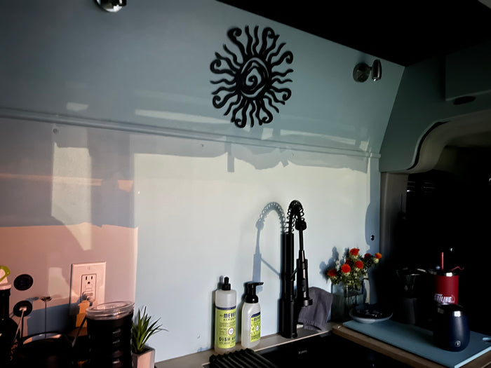 Stylish RV rental galley showcasing a functional sink, coffee corner, and decorative sun wall art.