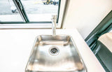Explore this RV rental's modern interior featuring a sleek stainless steel kitchen sink & faucet with outdoor views.
