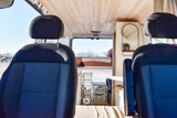 Spacious RV rental interior with front seats, wooden ceiling, cozy bed, and smart storage solutions for travel.