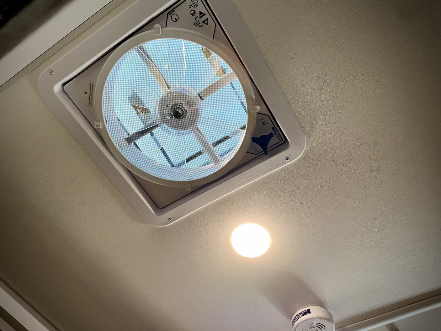 Overhead view in an RV rental: a ceiling MaxxFan ventilation system, bright light, and smoke detector provide comfort.
