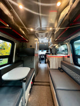 This RV rental features a well-equipped interior with a dinette, kitchen, and overhead bunk beds, leading to the cockpit.