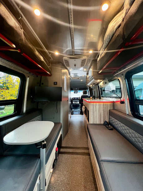 This RV rental features a well-equipped interior with a dinette, kitchen, and overhead bunk beds, leading to the cockpit.