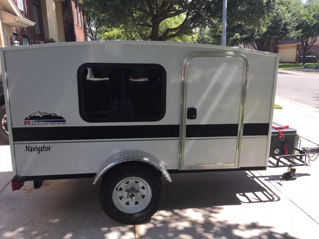 White, compact 'Runaway Navigator' RV rental, perfect for travel. Features a window, door, and chrome fender.