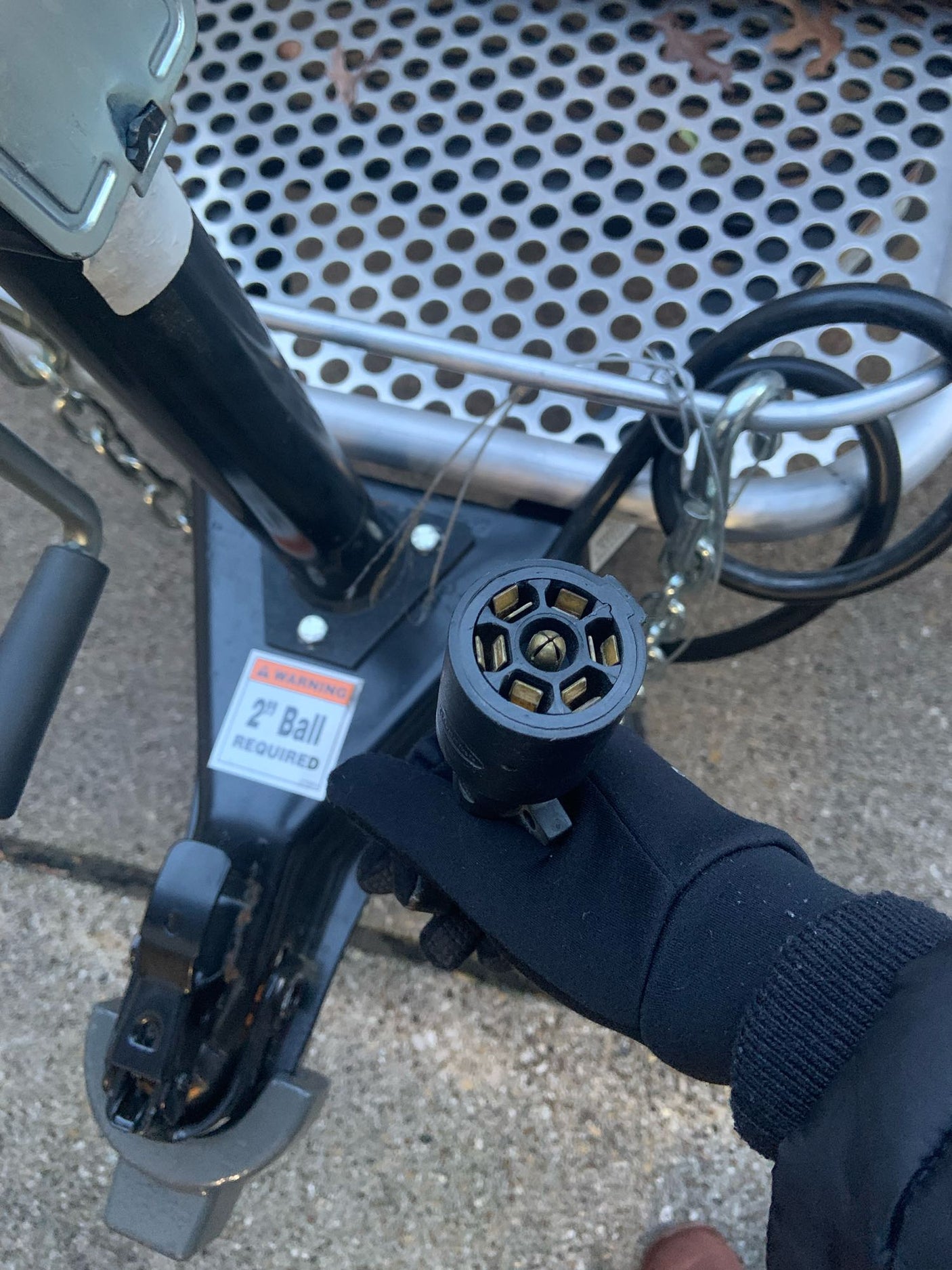Gloved hand holding a 7-pin trailer connector, preparing an RV rental hitch. Note: 2" ball required for safe towing.