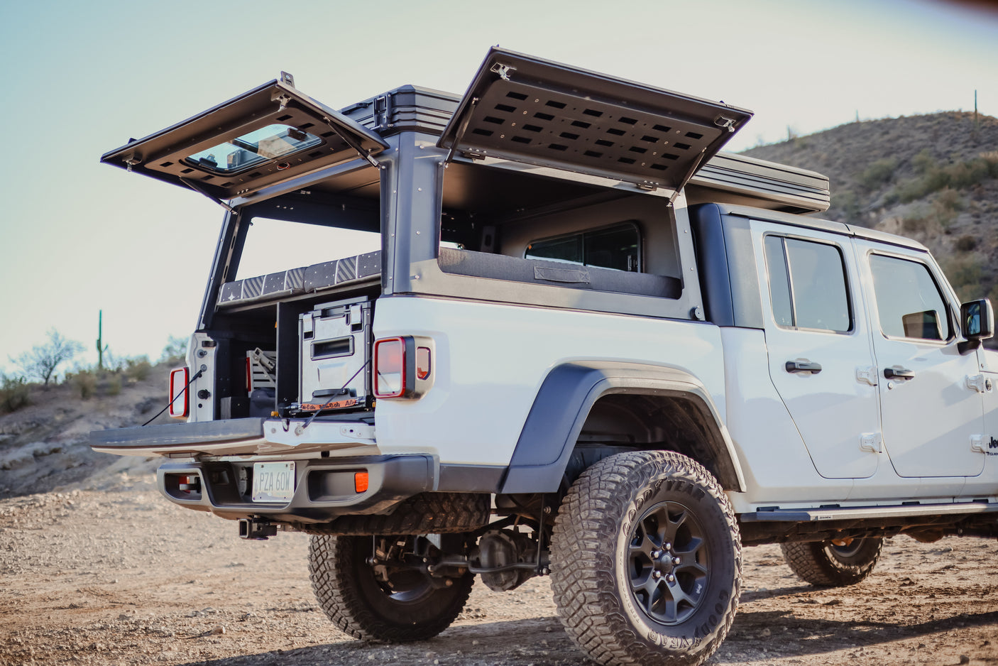 White Jeep Gladiator overland RV rental with open bed camper & rooftop tent, ready for adventure.