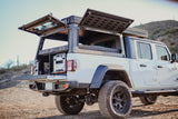 White Jeep Gladiator overland RV rental with open bed camper & rooftop tent, ready for adventure.